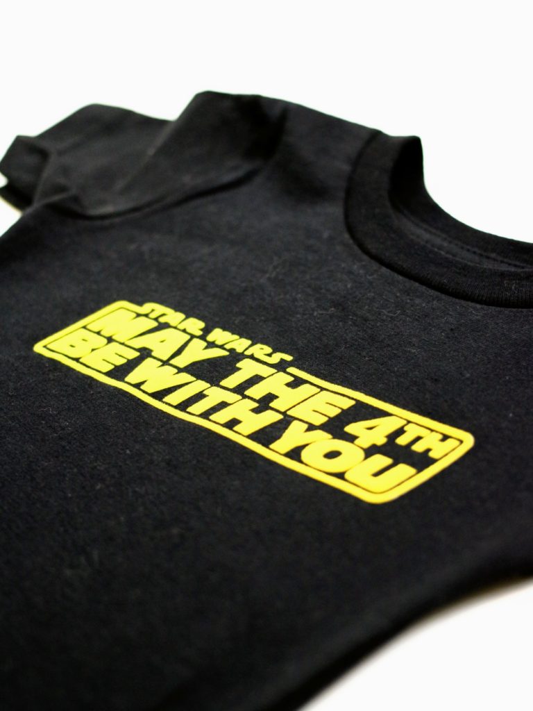 Get ready to celebrate Star Wars day with this DIY May The 4th Be With You t-shirt. Make your own t-shirt for under $5. Click through to see the steps so you can make one too!